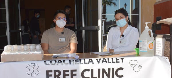 Students sitting at a welcome table at the Mecca Free Clinic